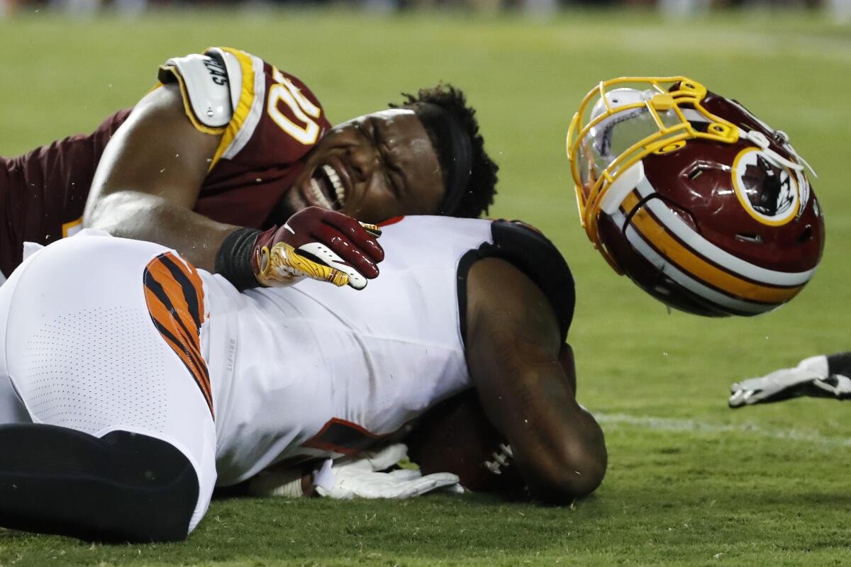 Washington linebacker Josh Harvey-Clemons loses his helmet as he tackles Cincinnati receiver Auden Tate. 