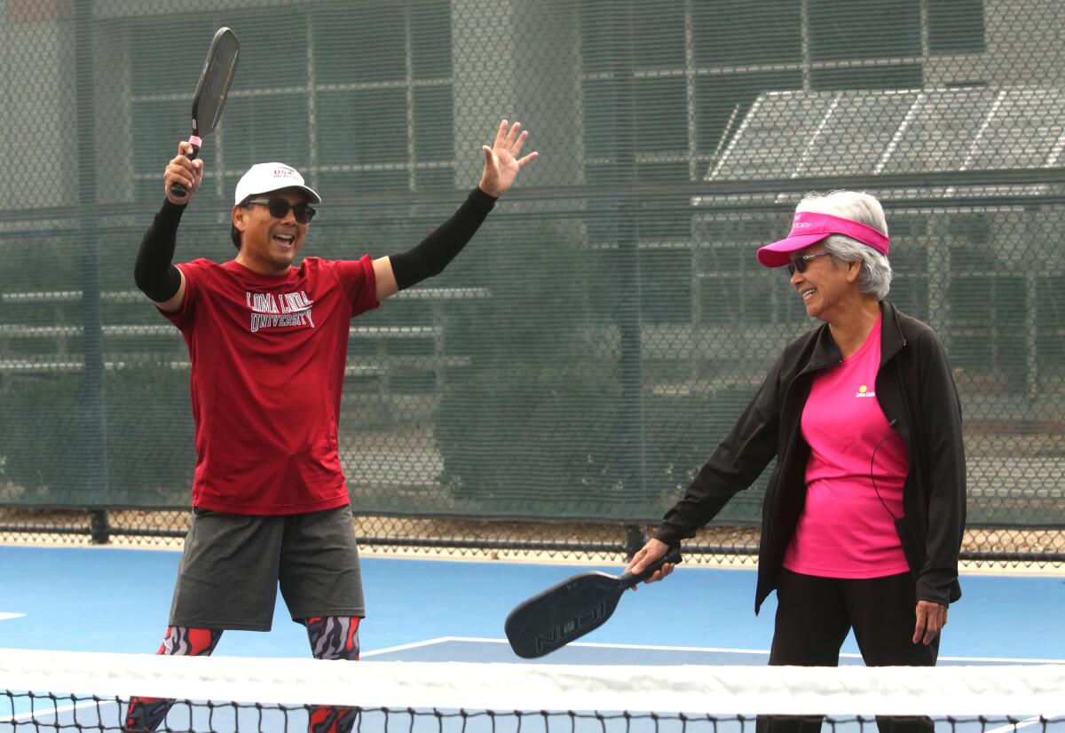 Dr. Loida Medina, 85, right, and her son Ernie Medina, 58, celebrate a point during a game of pickleball.