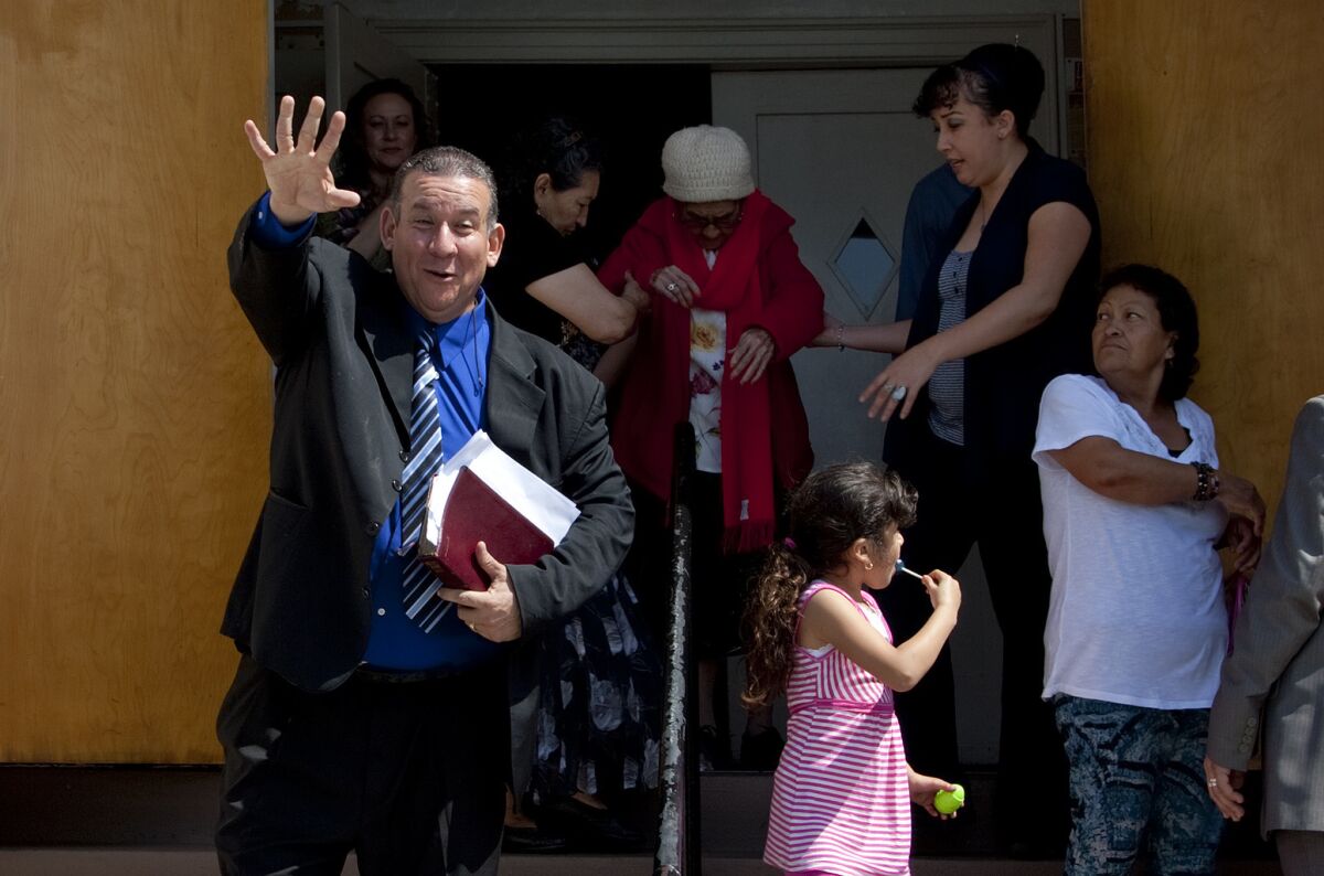 Pastor Luis Artiga, a former Bell councilman, clutches his Bible and waves to a church member after giving his sermon at the Bell Community Church on Sunday.