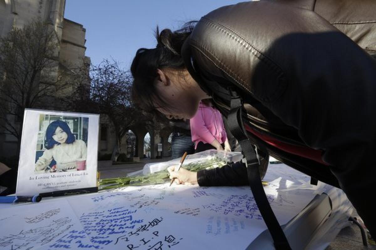 A photograph of Boston University student Lu Lingzi, who was killed in the Boston Marathon explosions, is on a table as a student writes a message on a board outside the school's Marsh Chapel before a vigil Wednesday.