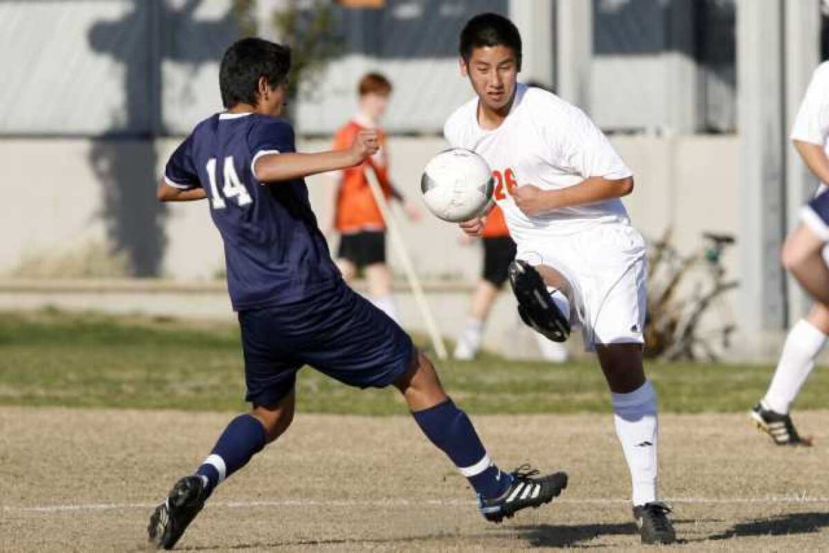 Flintridge Prep's Manny Perez, left, tries to block a kick from Pasadena Poly's Andy Chen during a game at Polytechnic School in Pasadena on Wednesday, February 8, 2012.