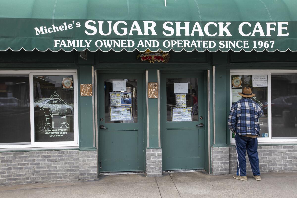 A man peers into the Sugar Shack Cafe in downtown Huntington Beach on March 18. 