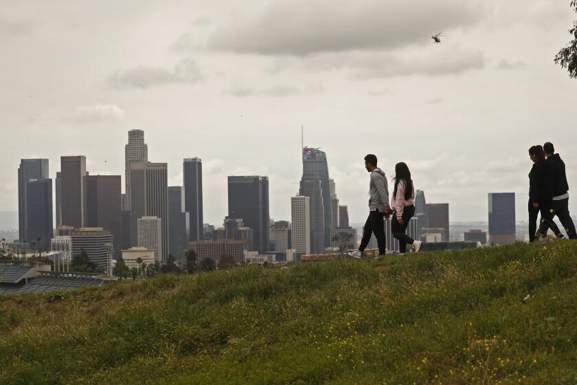 LOS ANGELES, CA - APRIL 13: Romell and Gloria Anthopoulos, left, and Anthony Riodriguez with Rosa Andrade, right, enjoy a walk through Elysian Park with a view of downtown Los Angeles on a cloudy Monday as it appears most people are staying home due to the coronavirus Covid-19 pandemic Los Angeles on Monday, April 13, 2020 in Los Angeles, CA. (Al Seib / Los Angeles Times)