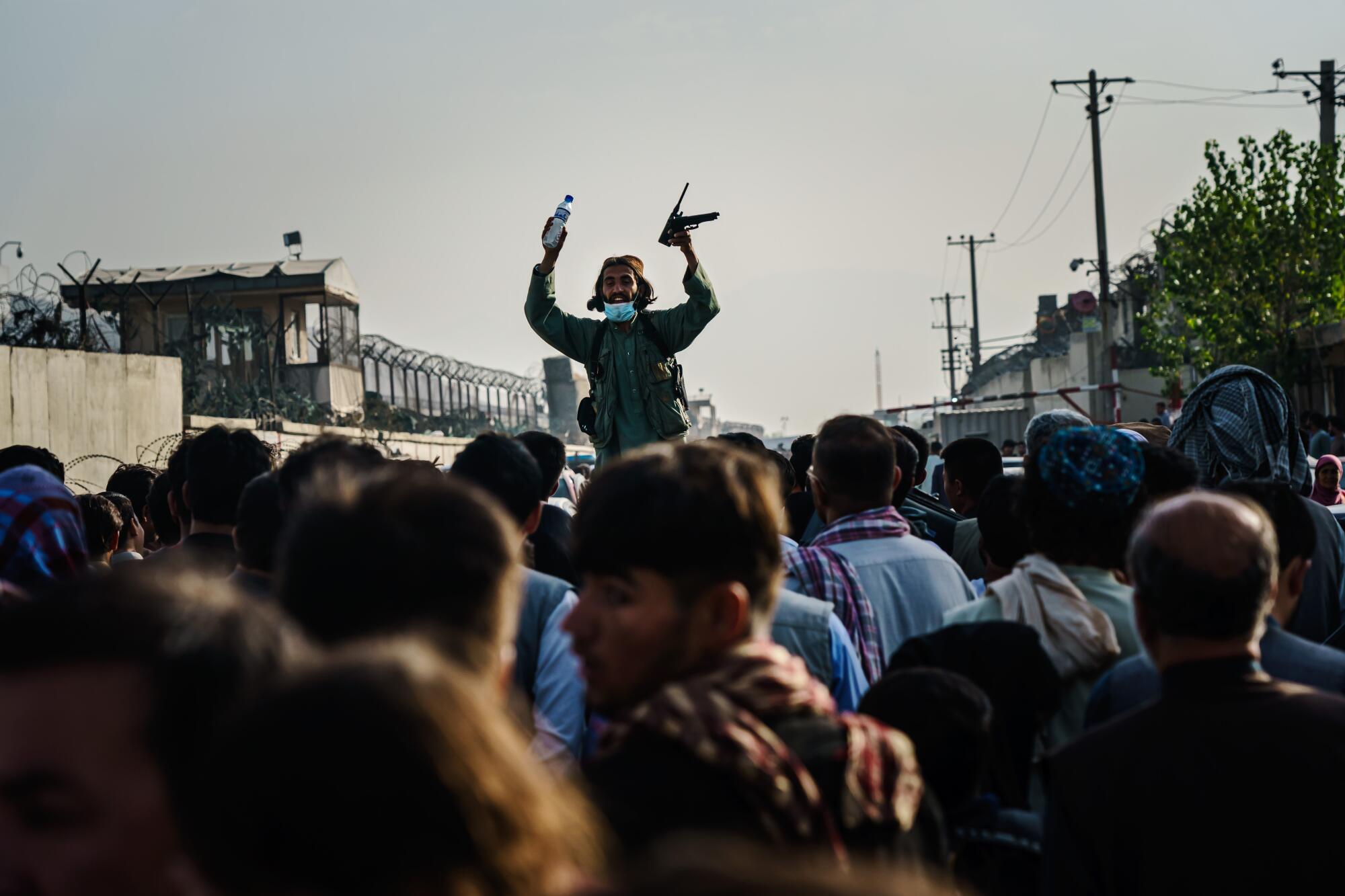 A Taliban fighter stands above the crowd while addressing it