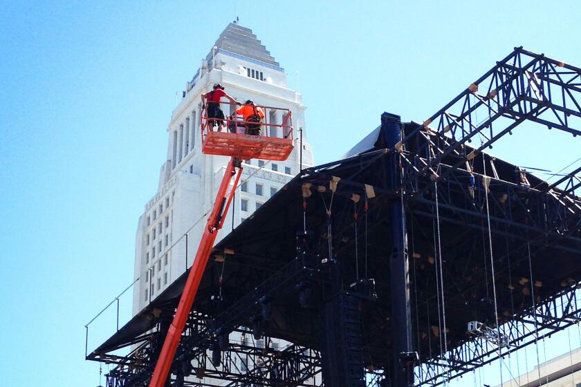 With City Hall looming tall in the background, crews work Aug. 28 to set up one of the Made In America concert stages adjacent to Grand Park.