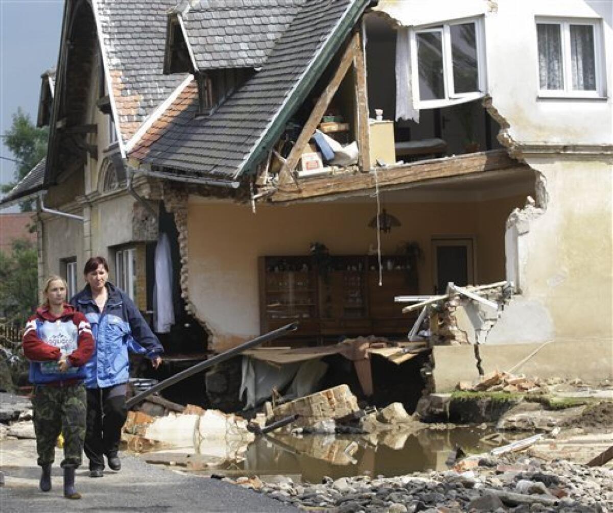 Residents carry water past a destroyed house after flash floods hit the village of Hermanice, Czech Republic, Sunday, Aug. 8, 2010. The flooding has struck an area near the borders of Poland, Germany and the Czech Republic. (AP Photo/Petr David Josek)