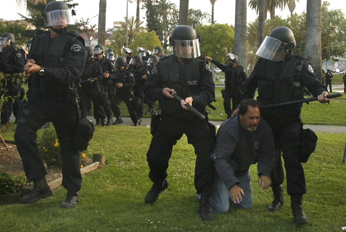 A Los Angeles police officer shoves a KCBS cameraman out of the way during a melee at MacArthur Park on May Day 2007.