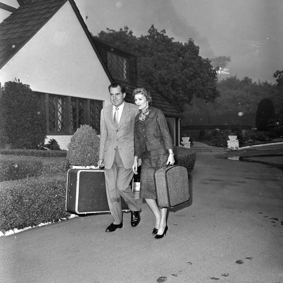 1961 file photo of former Vice President Richard Nixon and Mrs. Nixon carrying luggage as fire forces then to leave their rented home on Bundy Drive in Brentwood.