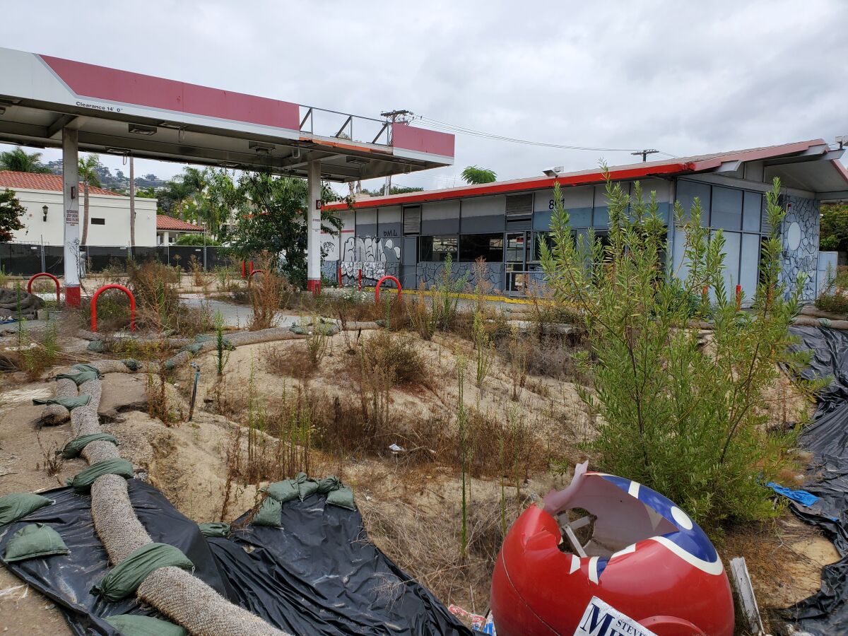 The former 76 gas station at 801 Pearl St. in La Jolla is partially demolished and overgrown with weeds.