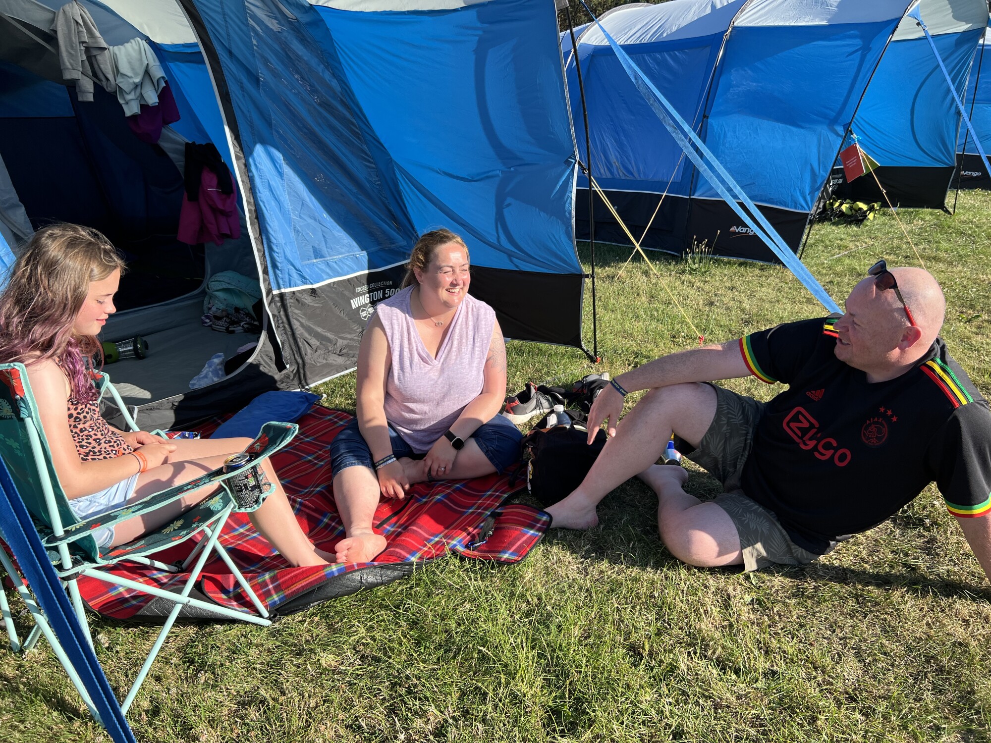 Simon and Elaine Neson sit outside their tent with daughter Emma