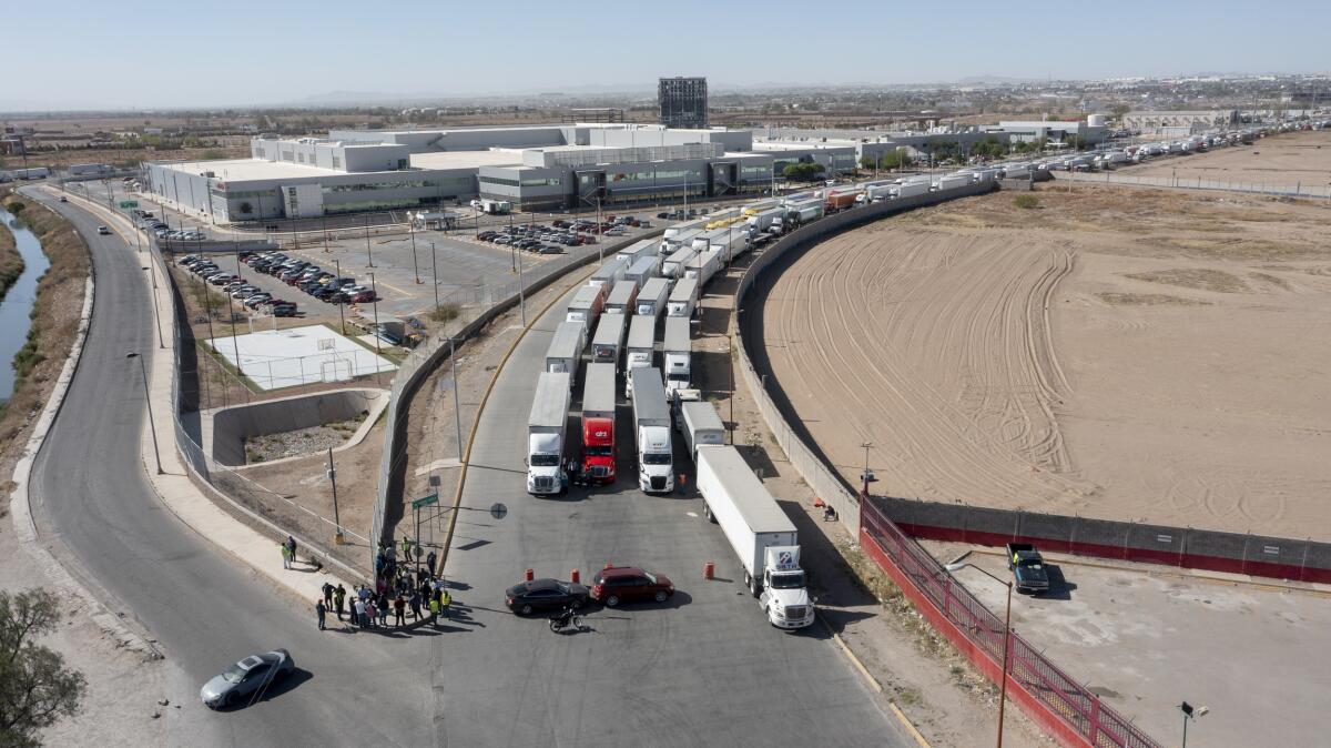 Four lanes of tractor-trailers wait in a long line at a U.S. port of entry.