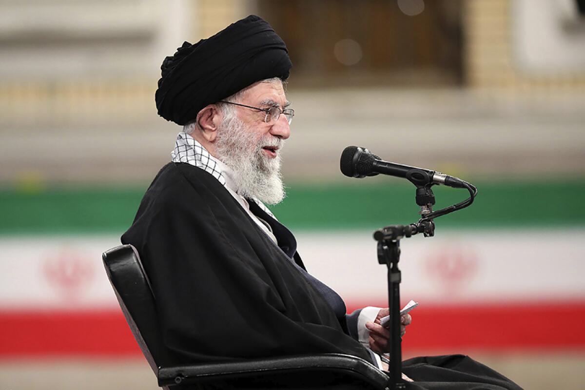 Supreme Leader Ayatollah Ali Khamenei sits in a chair next to a microphone