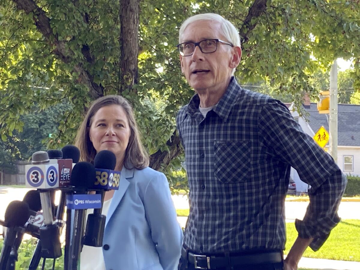 Wisconsin Democratic Gov. Tony Evers, is joined by his running mate state Rep. Sarah Rodriguez, as he speaks Wednesday, Aug. 10, 2022, in Madison, Wis. Gov. Evers says that his Republican opponent Tim Michels will not be able to distance himself from Donald Trump in the race, calling the former president's endorsement a "problem." (AP Photo/Scott Bauer)