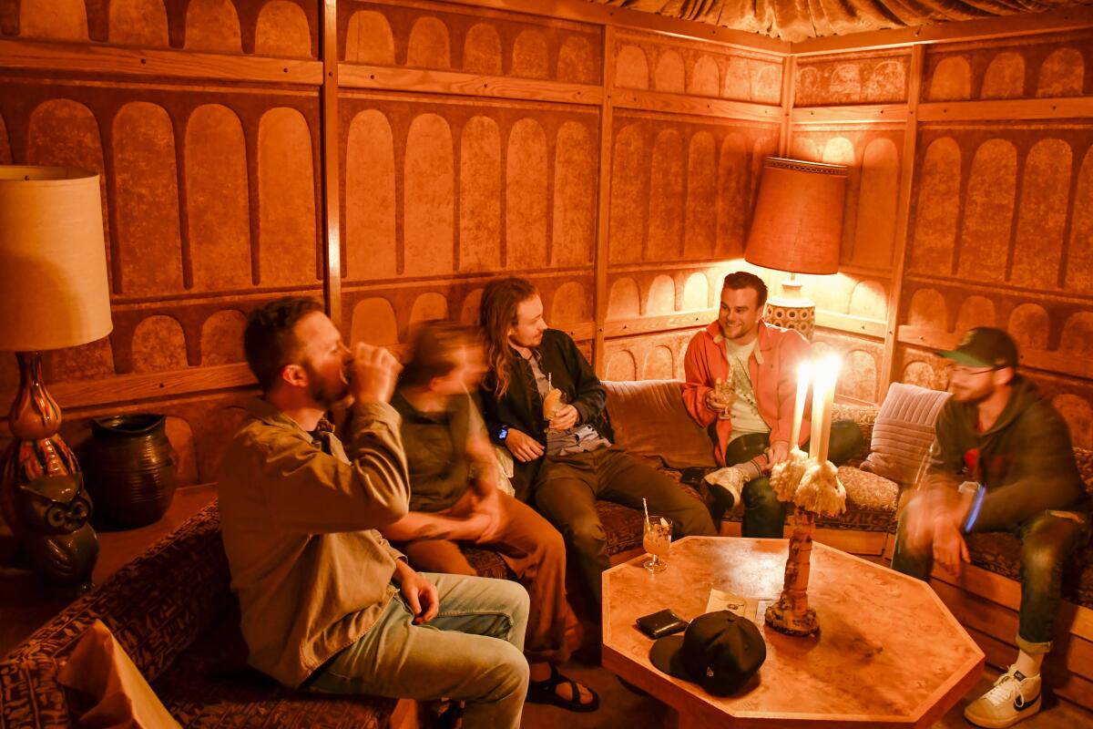 People sit around a low table in a room with wood-paneled walls