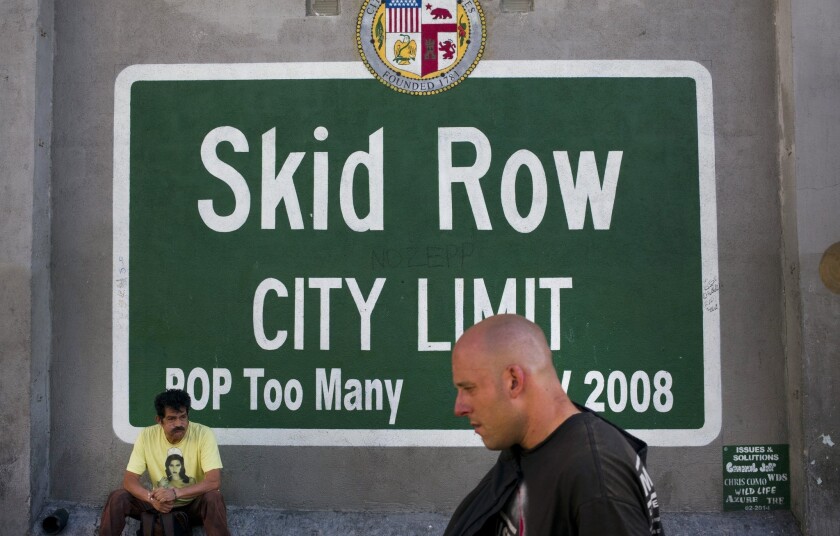 A man walks past a sign painted on a building in the Skid Row area of downtown Los Angeles on Nov. 17.