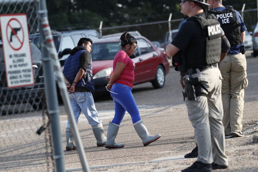 Two people are taken into custody at a Koch Foods Inc. plant in Morton, Miss., on Wednesday, Aug. 7, 2019. U.S. immigration officials raided several Mississippi food processing plants on Wednesday and signaled that the early-morning strikes were part of a large-scale operation targeting owners as well as employees. (AP Photo/Rogelio V. Solis)