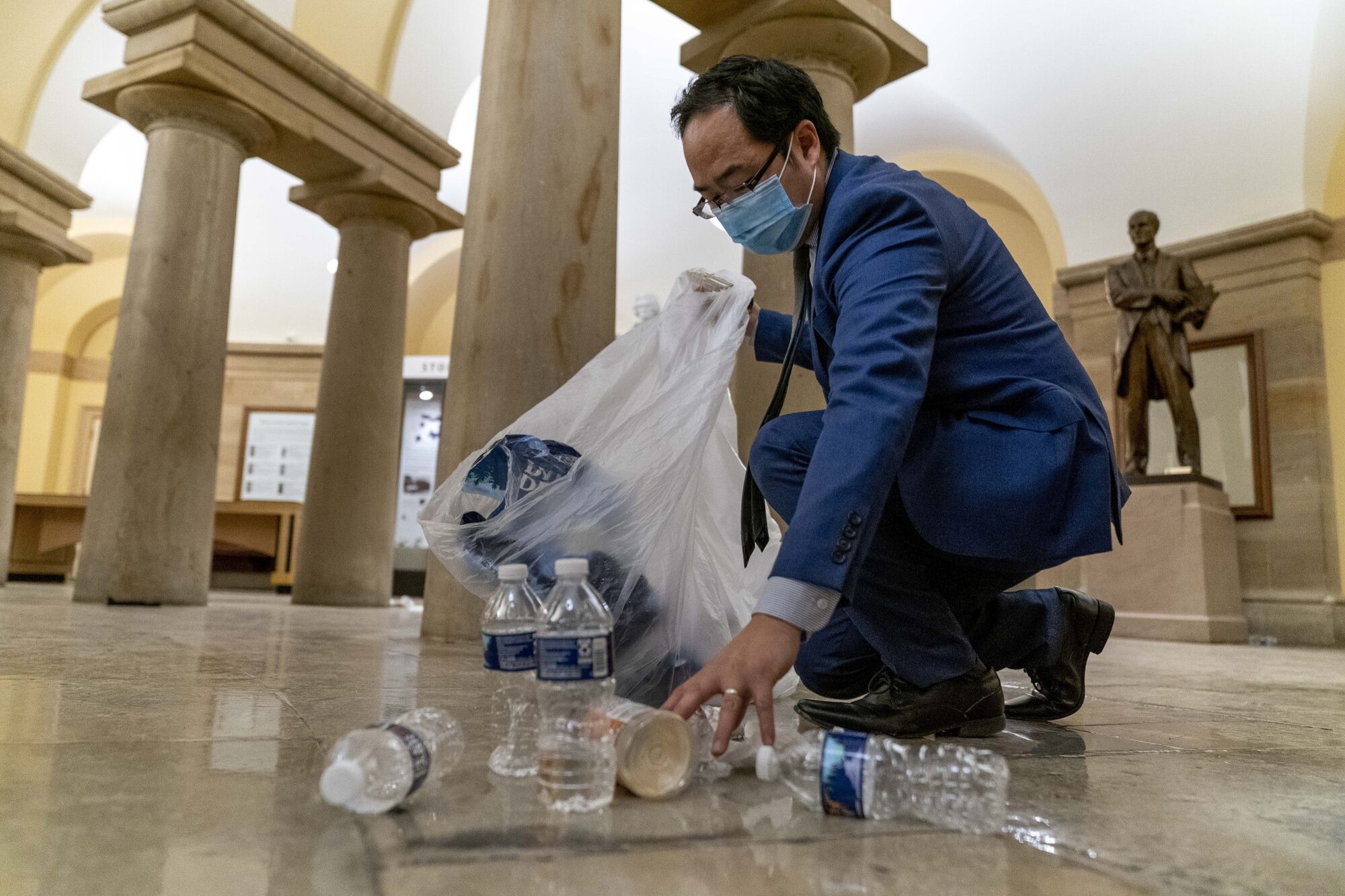 Rep. Andy Kim (D-N.J.) cleans up debris and trash strewn across the floor in the early morning hours.