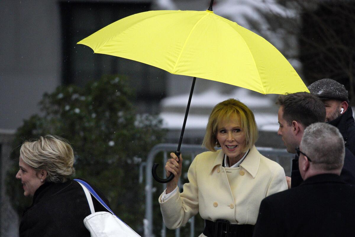 E. Jean Carroll holding a yellow umbrella while standing outside with others