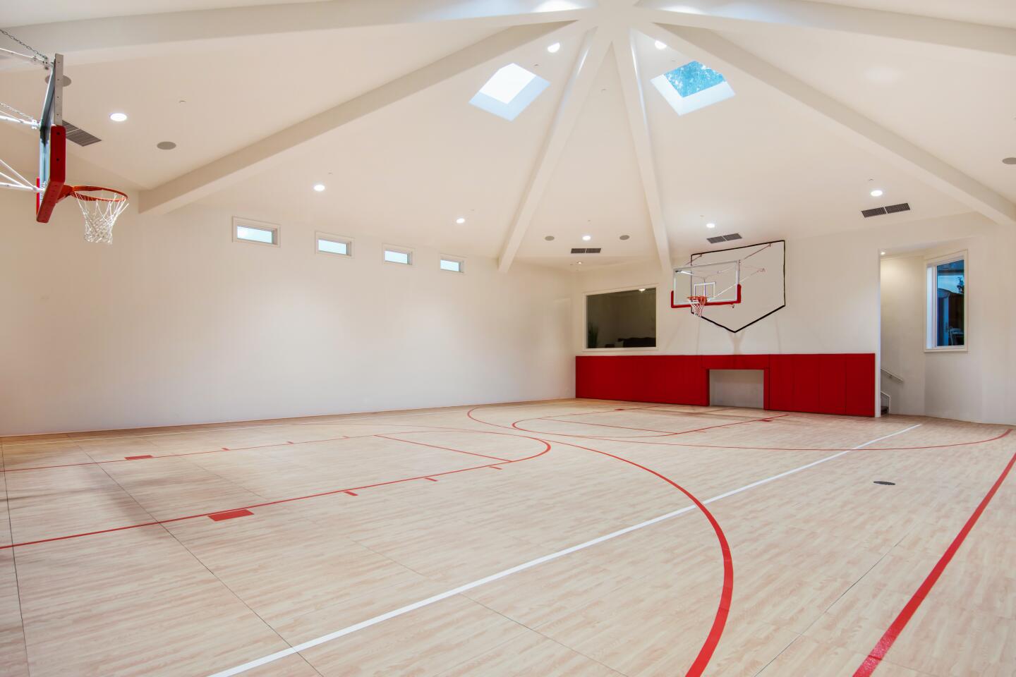 The basketball gymnasium has two hoops and a viewing box.