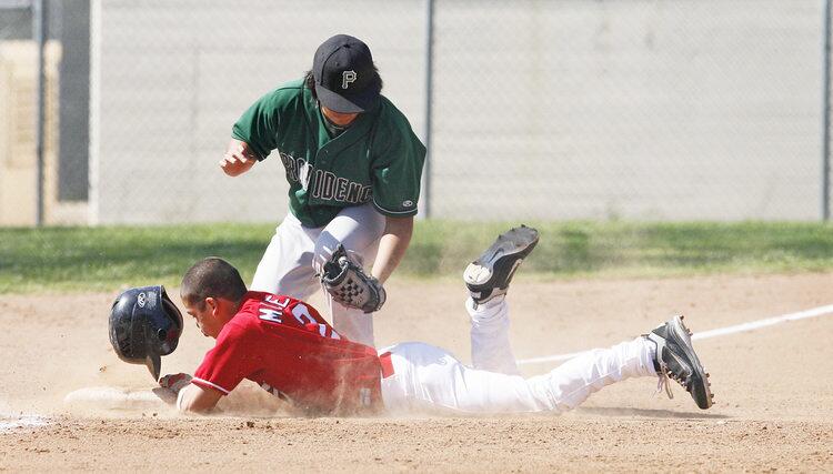 Bell-Jeff's Demitri Moreno, bottom, slides to third base while Providence's Mason Invmera tries to catch the ball during a game at Brace Canyon Park in Burbank on Tuesday, March 15, 2011. Bell-Jeff wins against Providence 20-1.
