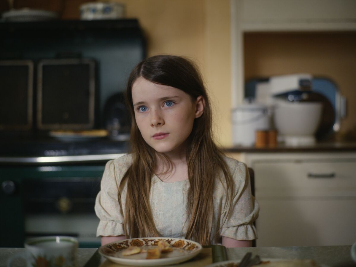 Catherine Clinch sits at a table with a plate of food in front of her in 'The Quiet Girl'