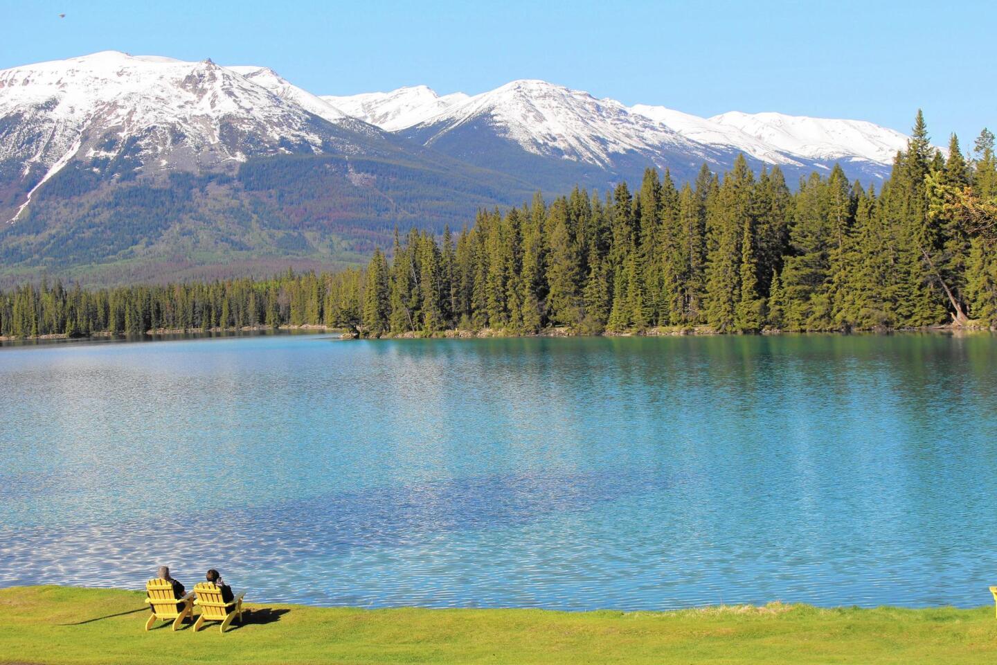Guests on the grounds of the Fairmont Jasper Park Lodge (opened 1922) savor morning sunshine and a view of Lac Beauvert and the Canadian Rockies.