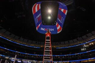 Chicago, Ill, Friday, August 16, 2024 - Photographer Claudia Zuno works from the top tall ladder to capture images of local politicians and party members on the DNC stage as preparations continue for the Democratic National Convention at the United Center. (Robert Gauthier/Los Angeles Times)