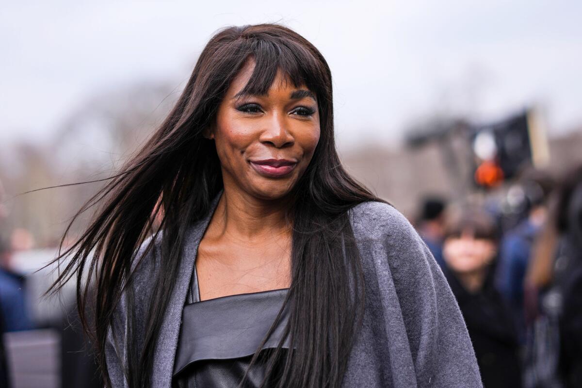Venus Williams wears a black shiny leather dress and a gray wool coat