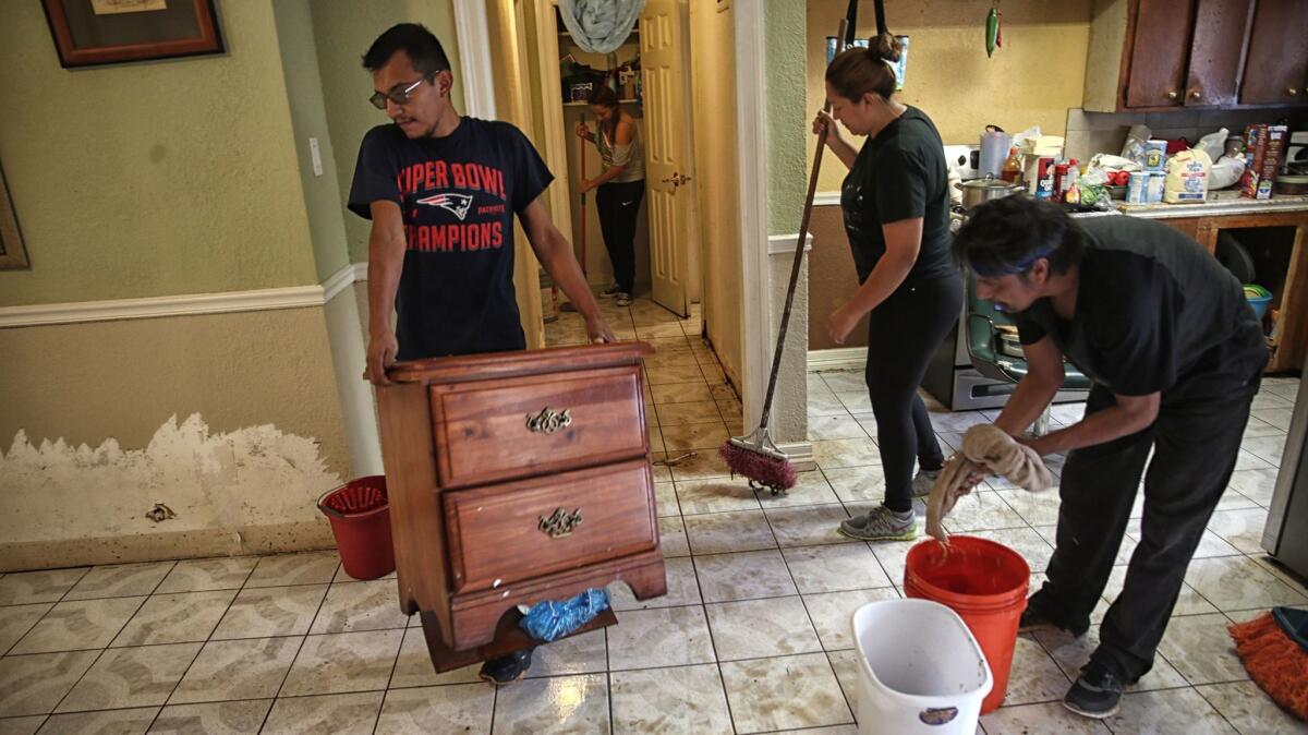Juan Figueroa removes damaged furniture as others clean his mother's flooded northeast Houston home.