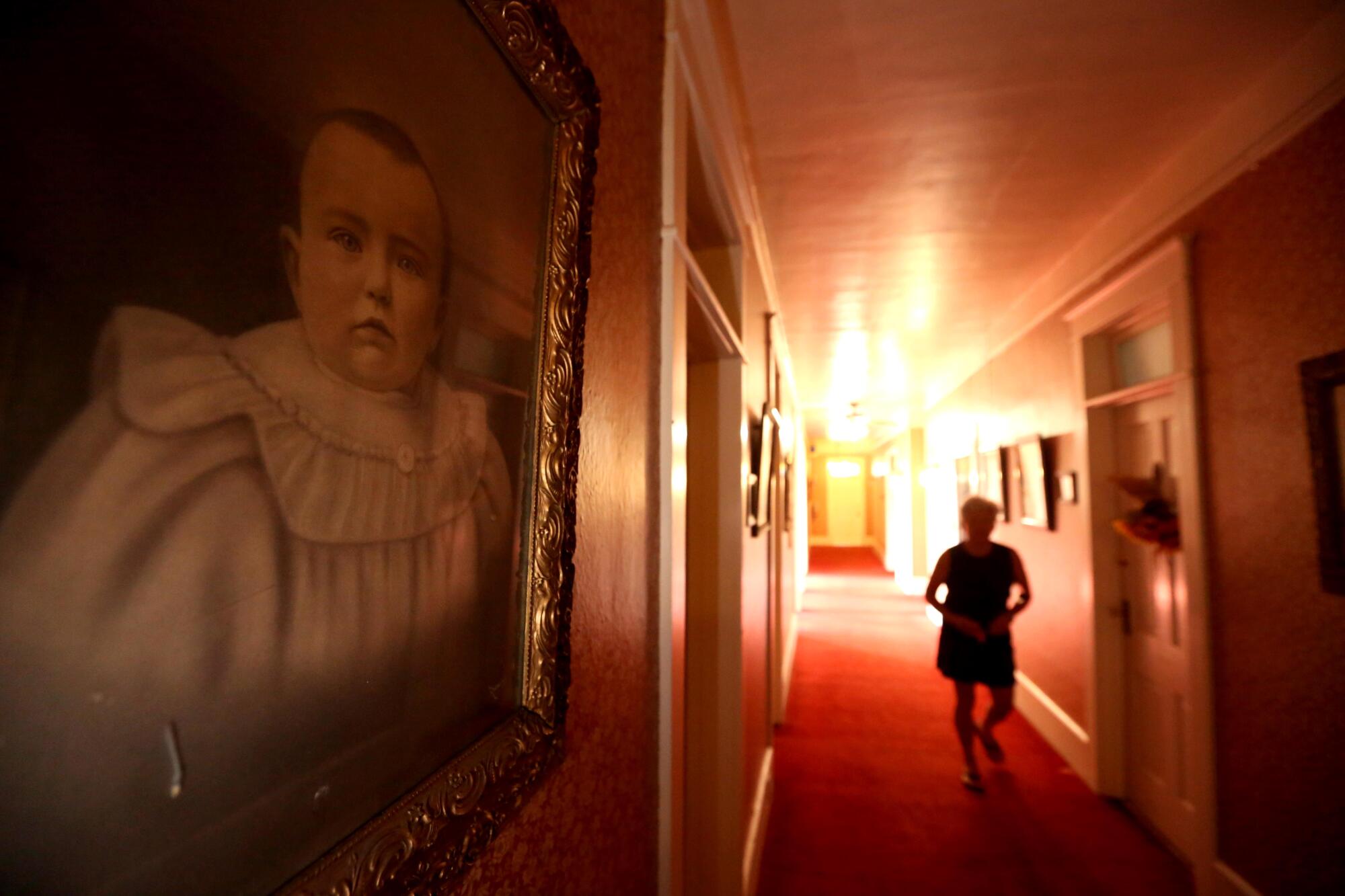 A woman walks down a hallway in the historic Niles Hotel in Alturas, Calif.