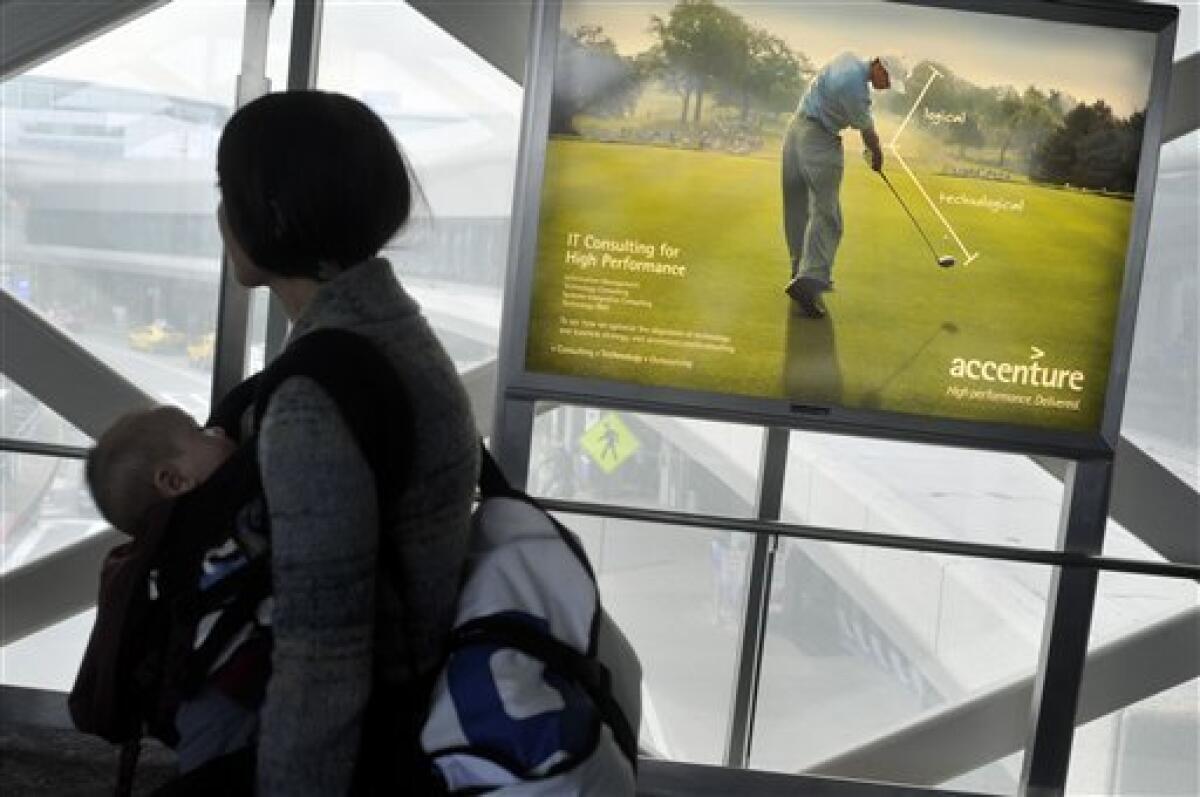 Travellers walk in front of an Accenture advertisement featuring Tiger Woods at San Francisco International Airport, Monday, Dec. 14, 2009. Accenture, which pinned its entire identity on the golfer, severed its ties with Woods on Sunday, days after he announced an indefinite leave from golf to work on his marriage after allegations of infidelity surfaced in recent weeks. (AP Photo/Russel A. Daniels)