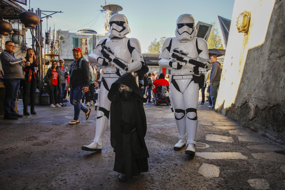 A child wearing a Kylo Ren costume is escorted by Stormtrooper cast members at Star Wars: Galaxy’s Edge in Orlando, Florida.