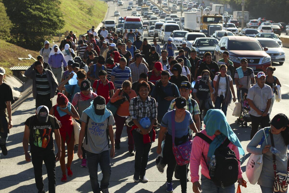 A large group of migrants traveling by foot along a highway.