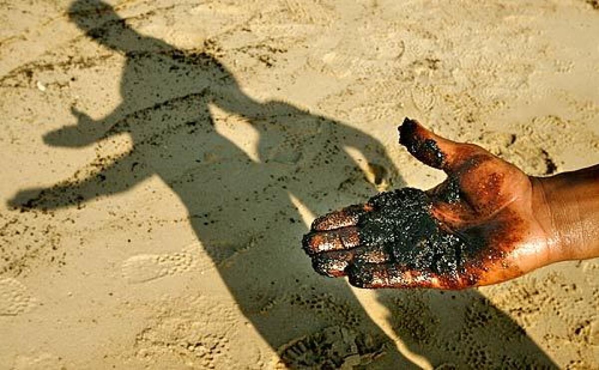 A man holds some of the oil-soaked sand at Ramlat al Baida beach in Beirut. Israeli forces attacked a power plant last month, releasing waves of oil that have covered the popular beach in black tar.