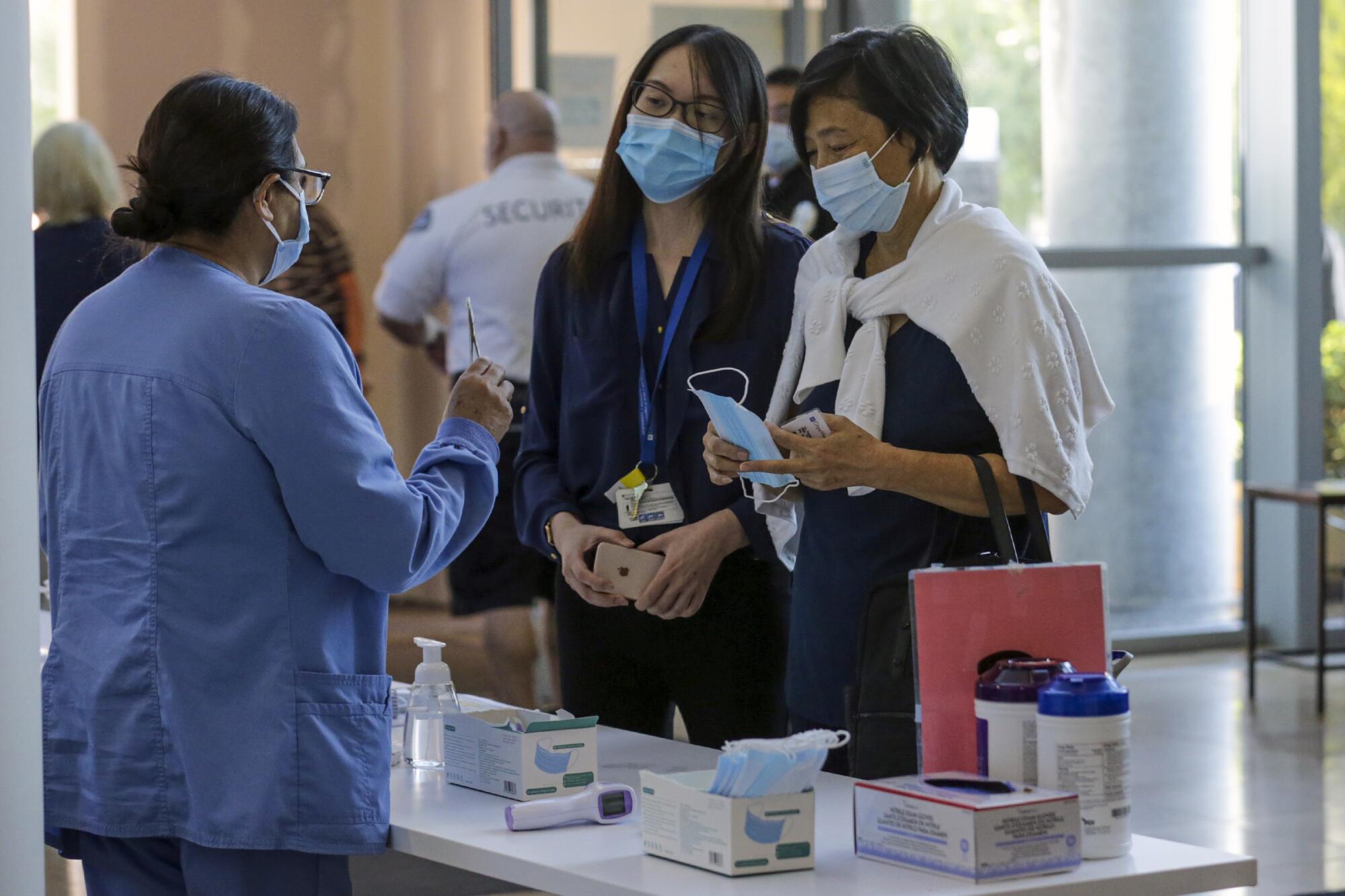 Whitney Cheng, left, escorts Yuyuan Lin through screening upon her arrival for chemotherapy at City of Hope Hospital