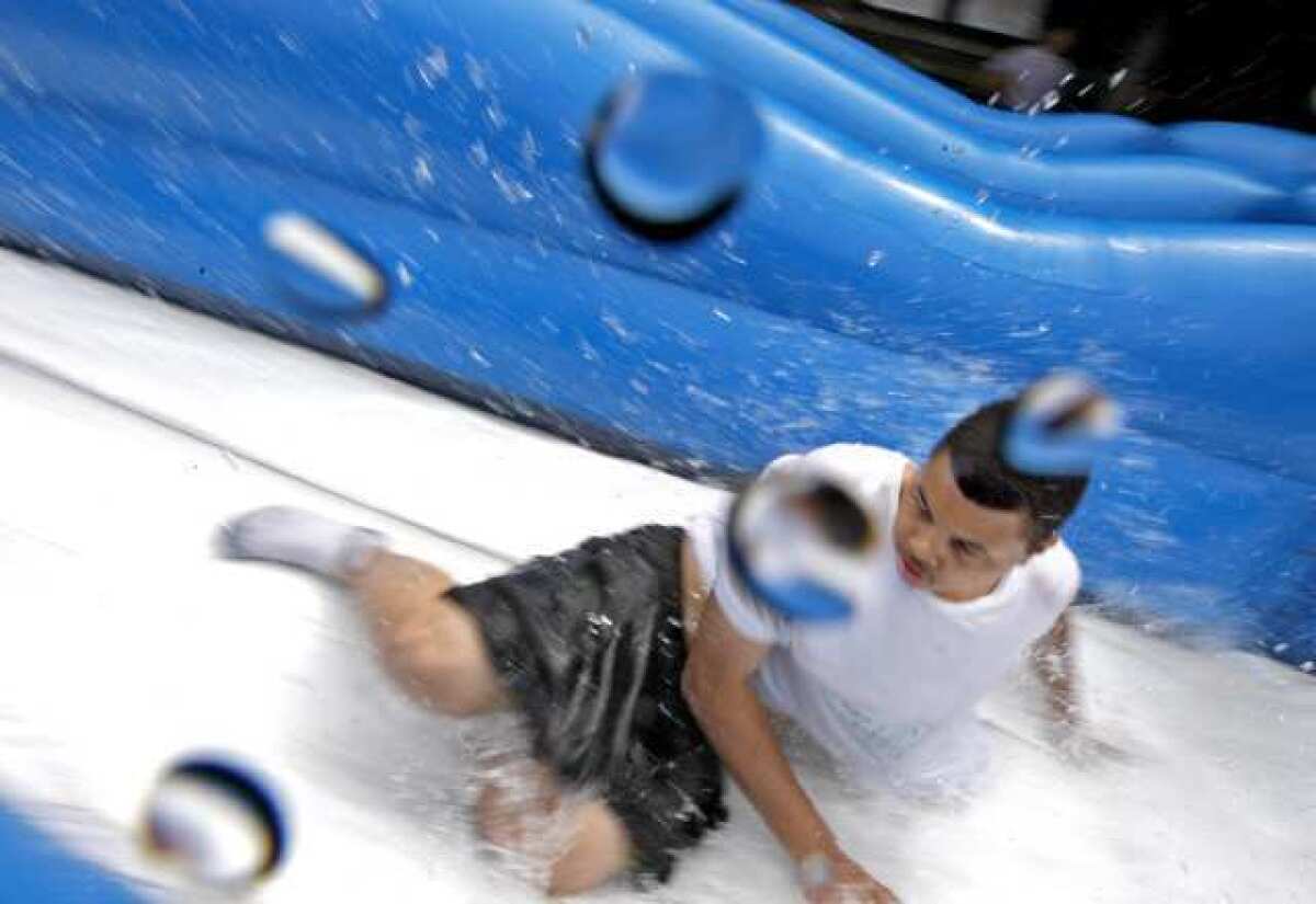 Tobinworld student Bryan splashes as he slides down a giant water slide set up on the central quad of the Glendale school Friday.