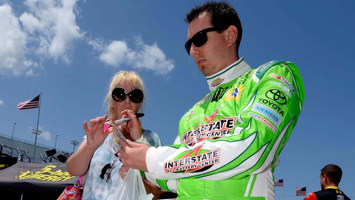 NASCAR driver Kyle Busch signs an autograph in the garage area during practice Friday for the Sprint Cup Coke Zero 400 at Daytona International Speedway.