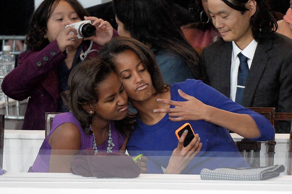 Sasha, left, and Malia Obama take a photo of themselves on a cellphone during the presidential inaugural parade.
