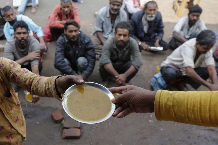 FILE - People wait for free food outside an eatery in Ahmedabad, India, Wednesday, Jan. 20, 2021. The prolonged pandemic and surging prices are undermining food security for millions of people in Asia, with 1.8 billion lacking access to healthy diets, a report by the UN’s Food and Agricultural Organization said Wednesday, Dec. 15, 2021. (AP Photo/Ajit Solanki, File)
