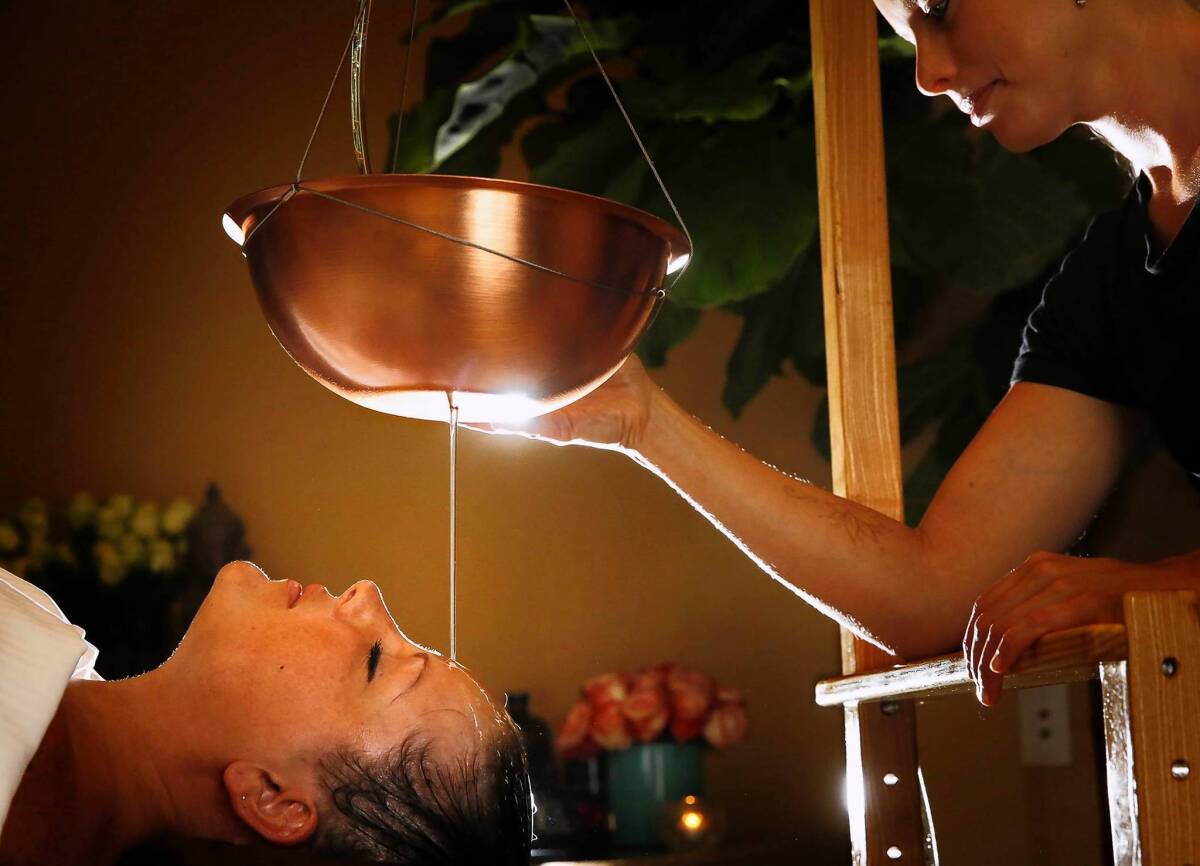 Senior spa therapist Kelie Micho directs a stream of warm sesame oil from a copper bowl on the the "third eye" of guest Monica Graves at the Chopra Center Spa at La Costa Resort and Spa in Carlsbad. The Shirondhara Therapy is believed to calm the central nervous system and is considered one of the spa's most spiritual experiences. The 65-minute session includes a full-body massage and costs $205.