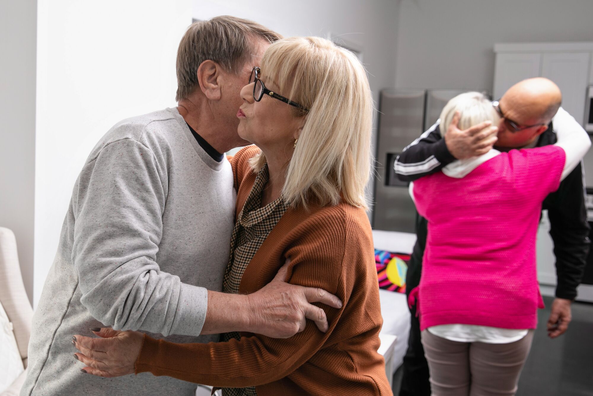 Two couples kiss hello
