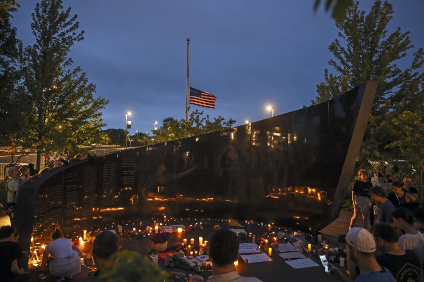 Dozens of mourners gather for a vigil in downtown Highland Park, Illinois, on Tuesday after a mass shooting on Monday.