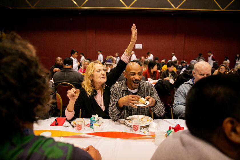 Sandra Bales, 68 and Michael Mallory, 49, enjoy their meals at the Salvation Army's 36th annual Thanksgiving Day meal in Golden Hall by serving food to anyone looking for a warm meal on November 28, 2019 in San Diego, California. "I'm very thankful to be out of the rain," said Bales, who lives in the Golden Hall shelter.