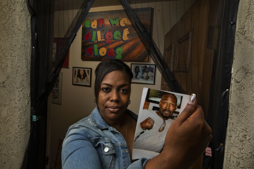 SAN PEDRO, CA-APRIL 26, 2019: Lora King, daughter of Rodney King, holds a photograph of her late father, while standing at the front entrance of her home in San Pedro. Monday marks the 27 year anniversary of the L.A. Riots, a defining moment in LA history that shaped the city and led to police reform. Lora King is creating a foundation and scholarship in his honor. (Mel Melcon/Los Angeles Times)