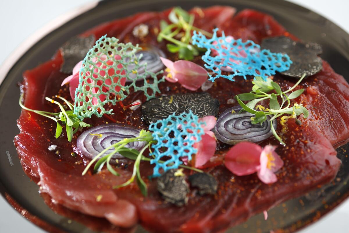 Thinly sliced Local Bluefin Tuna Carpaccio is topped with shallot, truffle, ginger crystals, lemon zest and microgreens.