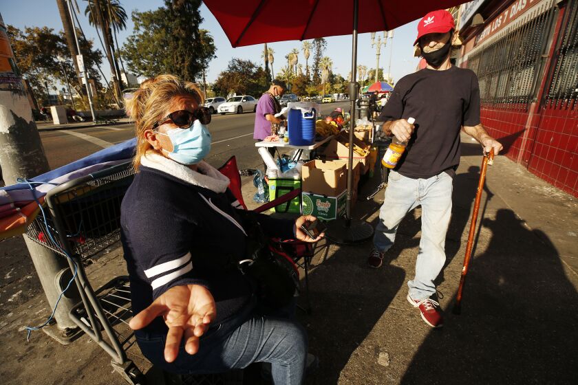 LOS ANGELES, CA - NOVEMBER 19: Elizabeth Medina, left, who has a been selling fruit from her stand at the corner of South Alvarado and 7th Street across from MacArthur Park for nearly 20 years is worried about the closures that may come with the surge in Covid cases. "There are many more homeless in the park now because of the virus. I fear that I may become homeless if closures come and if the government doesn't help," She said. This afternoon California Gov. Gavin Newsom announced a mandatory overnight stay-at-home order that will be instituted throughout most of California to combat a surge in new coronavirus cases, a measure that comes just days after the governor enacted a dramatic rollback of reopening in much of the state. "The virus is spreading at a pace we haven't seen since the start of this pandemic and the next several days and weeks will be critical to stop the surge. We are sounding the alarm," Newsom said in a statement released Thursday afternoon. "It is crucial that we act to decrease transmission and slow hospitalizations before the death count surges. We've done it before and we must do it again." MacArthur Park on Thursday, Nov. 19, 2020 in Los Angeles, CA. (Al Seib / Los Angeles Times