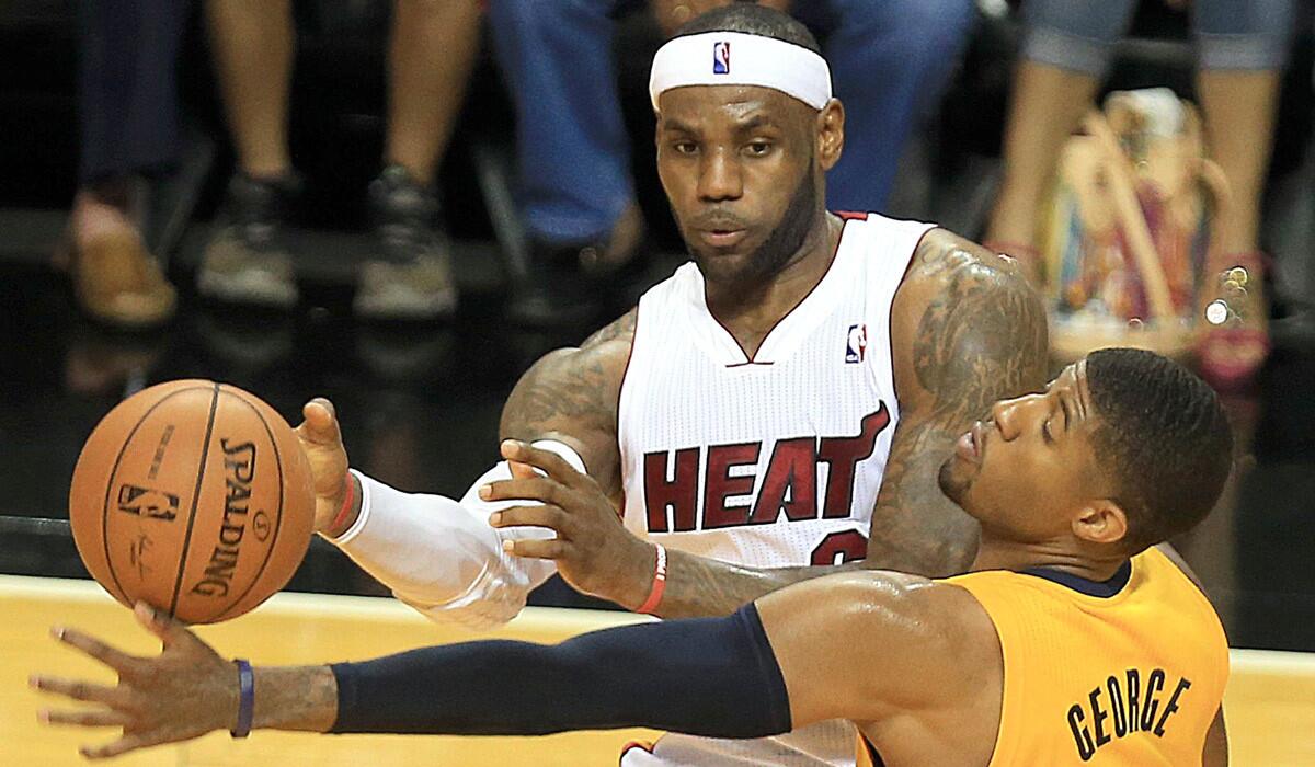 Heat forward LeBron James sends a pass past Pacers forward Paul George in the second quarter of Game 3 on Saturday night in Miami.