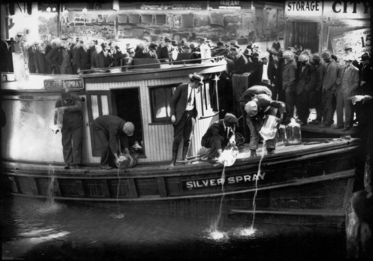 In this 1922 photo spectators gather by the side of captured rum runner, Silver Spray, as they watch prohibition agents pour "white lightning" from the five-gallon bottles on the deck into the Elizabeth River, Norfolk, Va. The Prohibition Era, which lasted from Jan. 17, 1920, until December 1933, is now viewed as a failed experiment that glamorized illegal drinking.