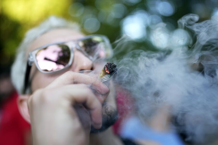 A youth smokes marijuana during the Open Plaza festival organized by the Granjamadre marijuana farm, in Asuncion, Paraguay, Sunday, June 4, 2023. (AP Photo/Jorge Saenz)