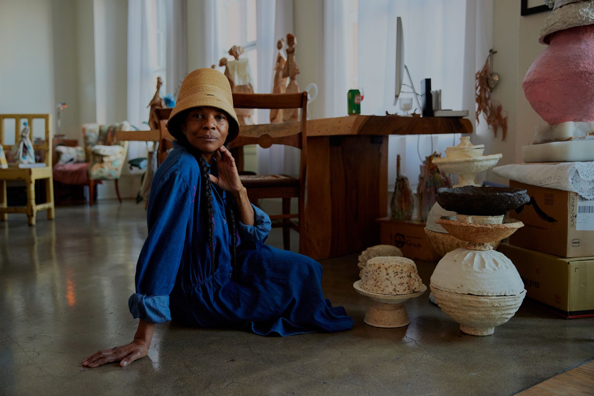 Natalia Pereira at her home and studio, AD105, seated alongside stacks of her paper mache bowls.